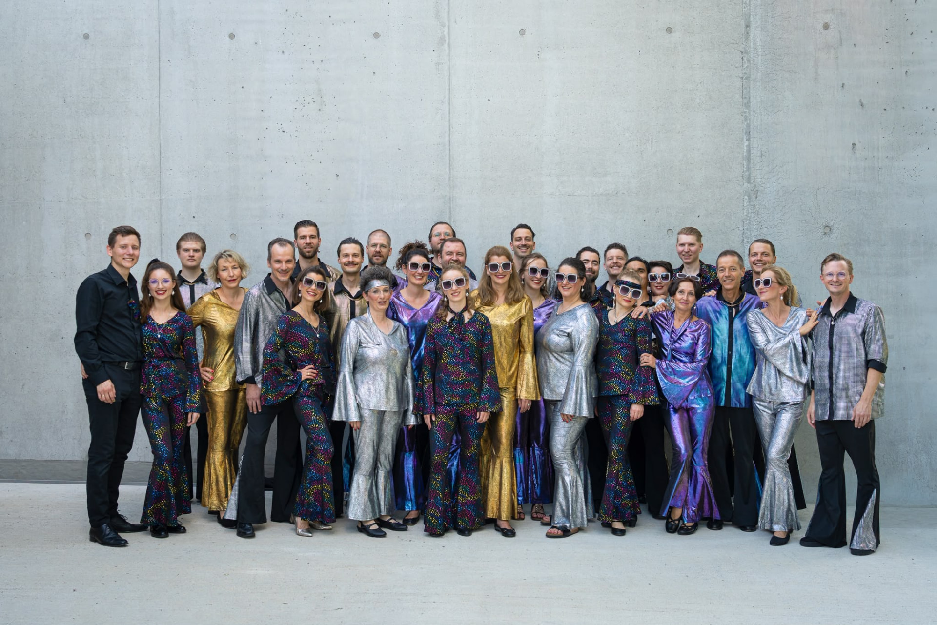 YURIKO gemeinsam in glitzernden Konzertoutfits vor einer hellen Betonwand